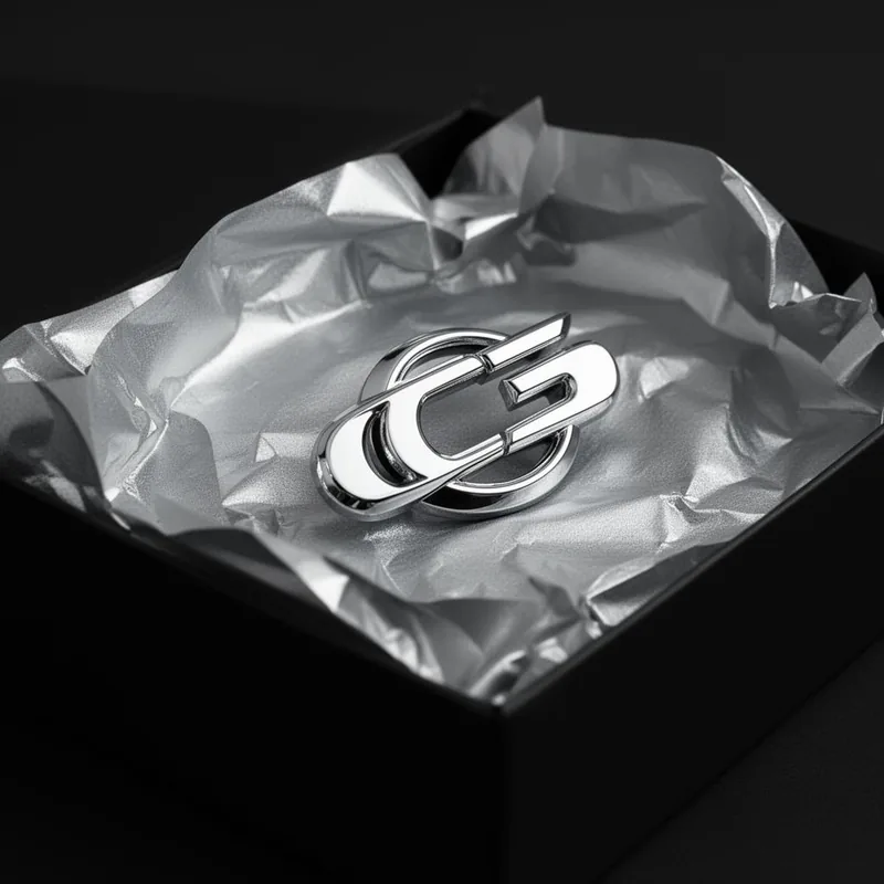 Close-up of chrome badge being lifted from premium packaging